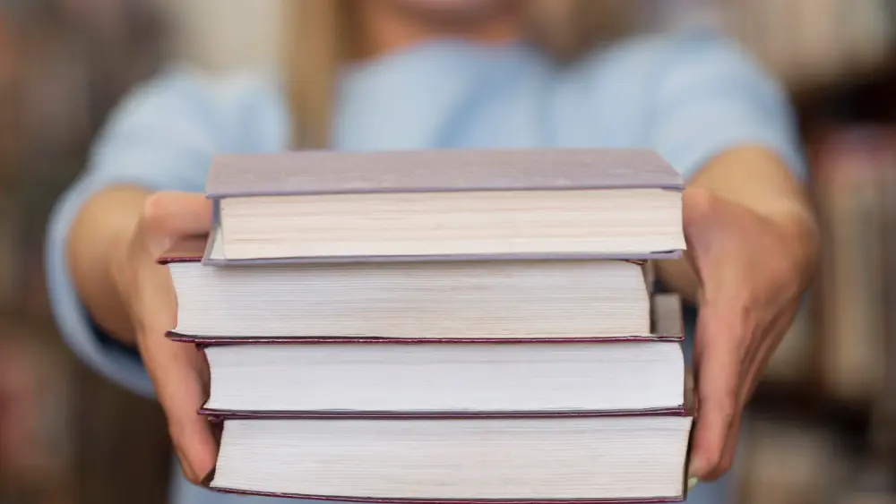 Eine Person hält mehrere Bücher in den Händen, ideal für Expertenbuch Selfpublishing.