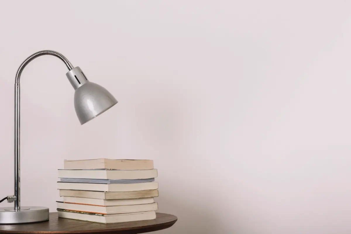 Ein Tisch mit einer Lampe und einem Stapel Bücher, ideal für sachbuch schreiben lassen.