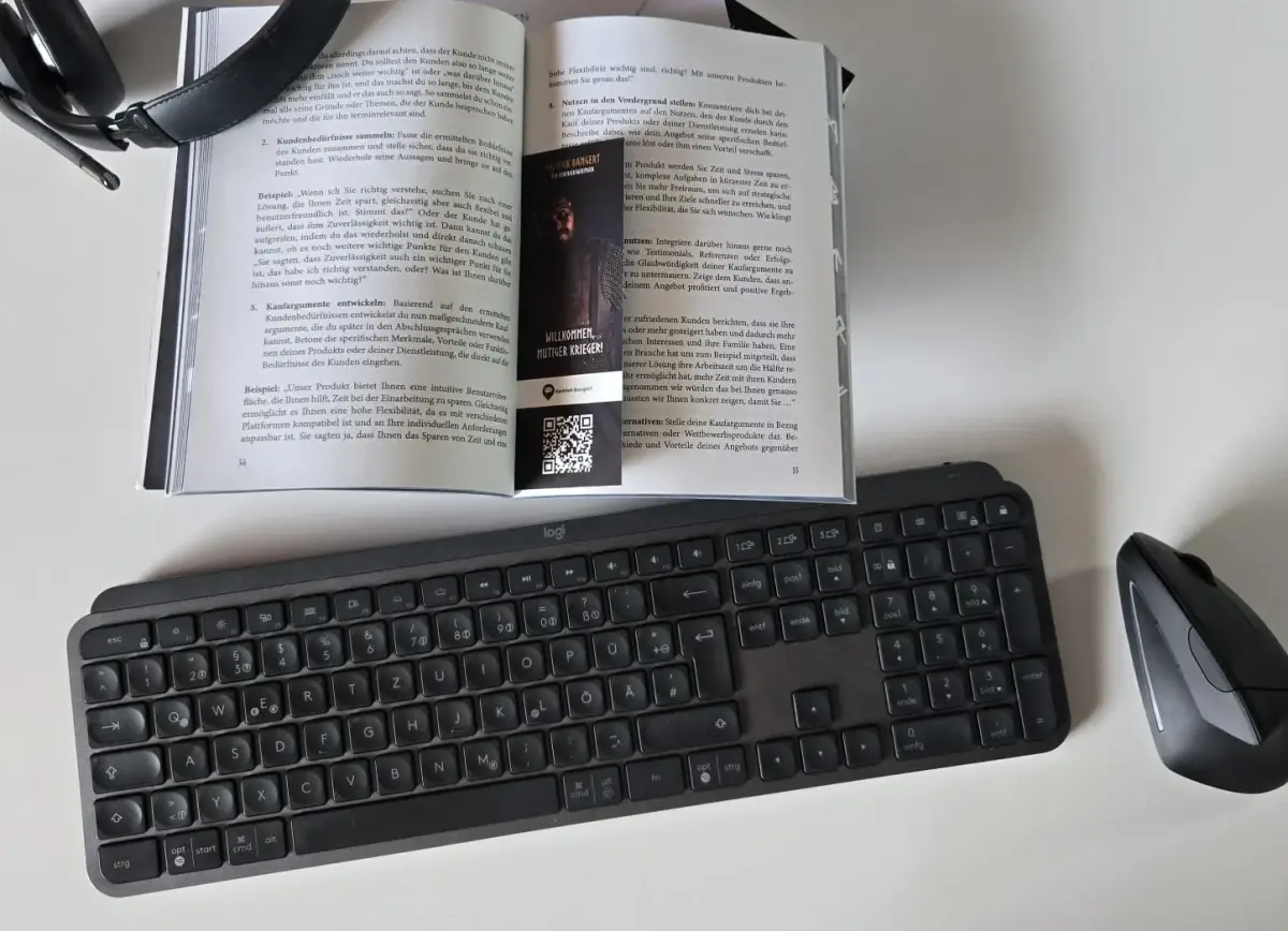 Offenes Buch über Coaching mit Tastatur und Maus auf dem Tisch.