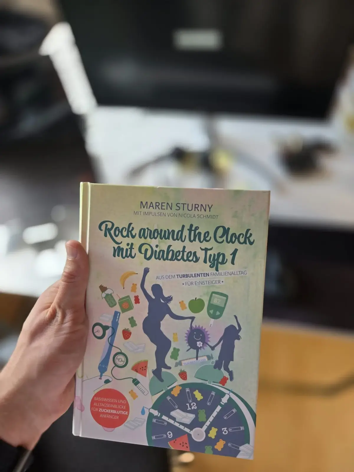 Buchcover von 'Rock around the Clock mit Diabetes Typ 1' in der Hand.