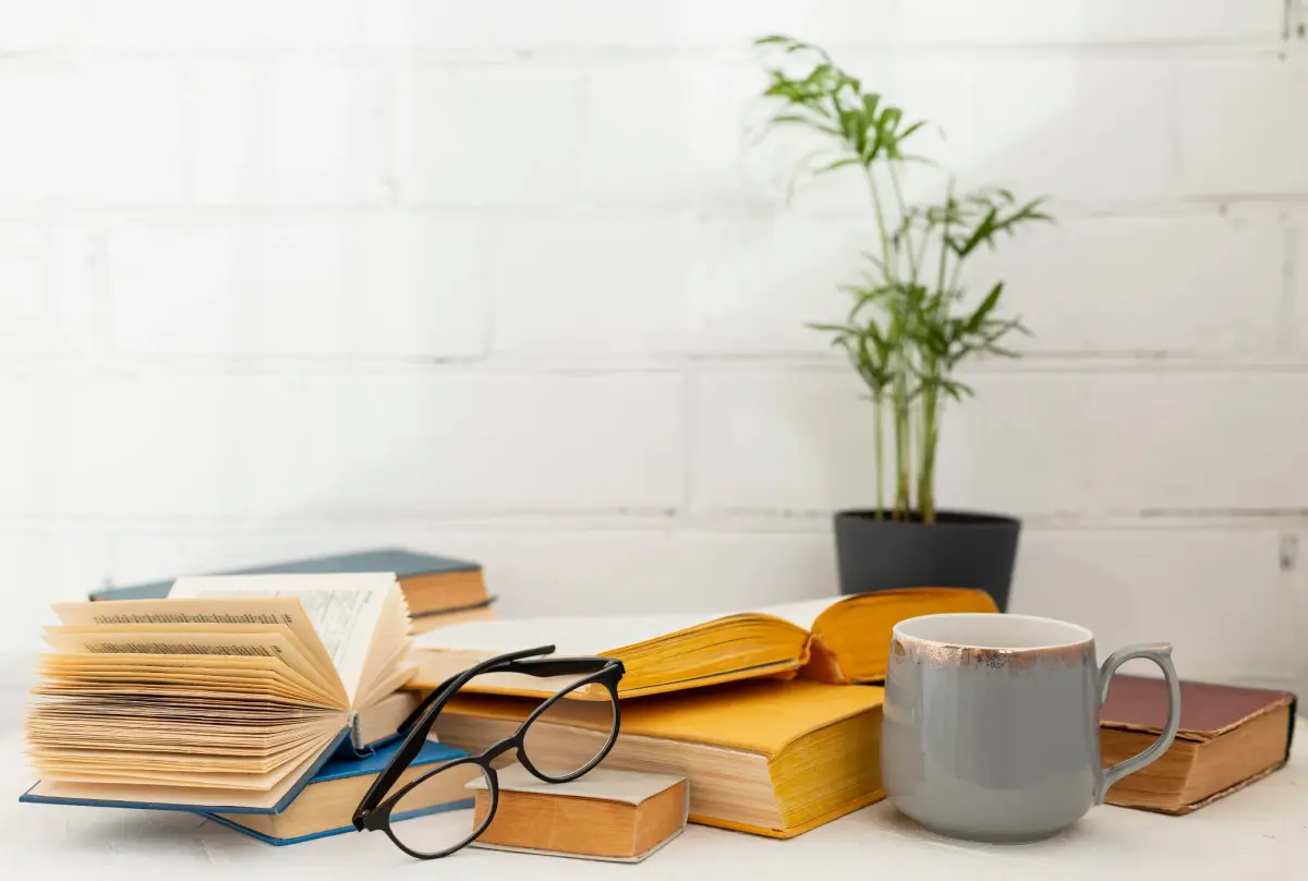 Auf dem Tisch liegen Bücher und eine Tasse Kaffee, ideal für dein Buchprojekt.