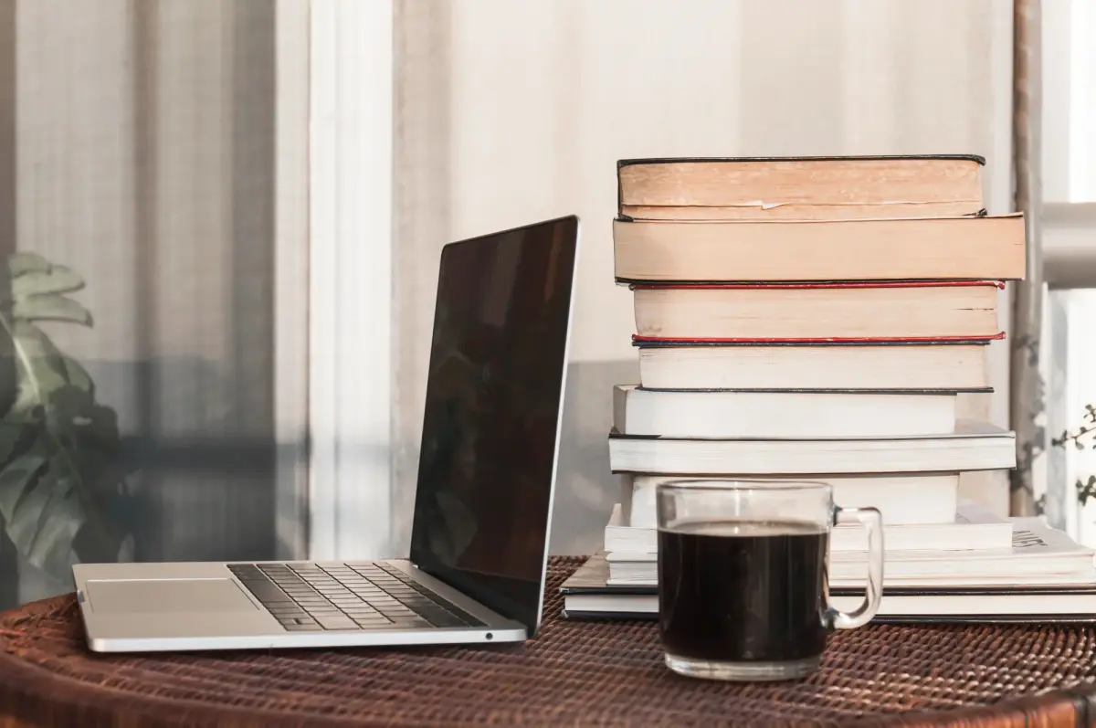 Ein Laptop und ein Kaffee neben einer Stapel Bücher als Leadmagnet.