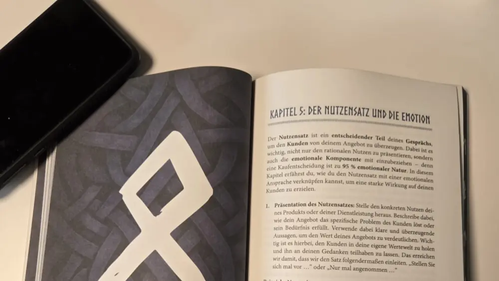 Aufgeschlagenes Buch zum Thema Buch schreiben für Medienpräsenz mit Smartphone.