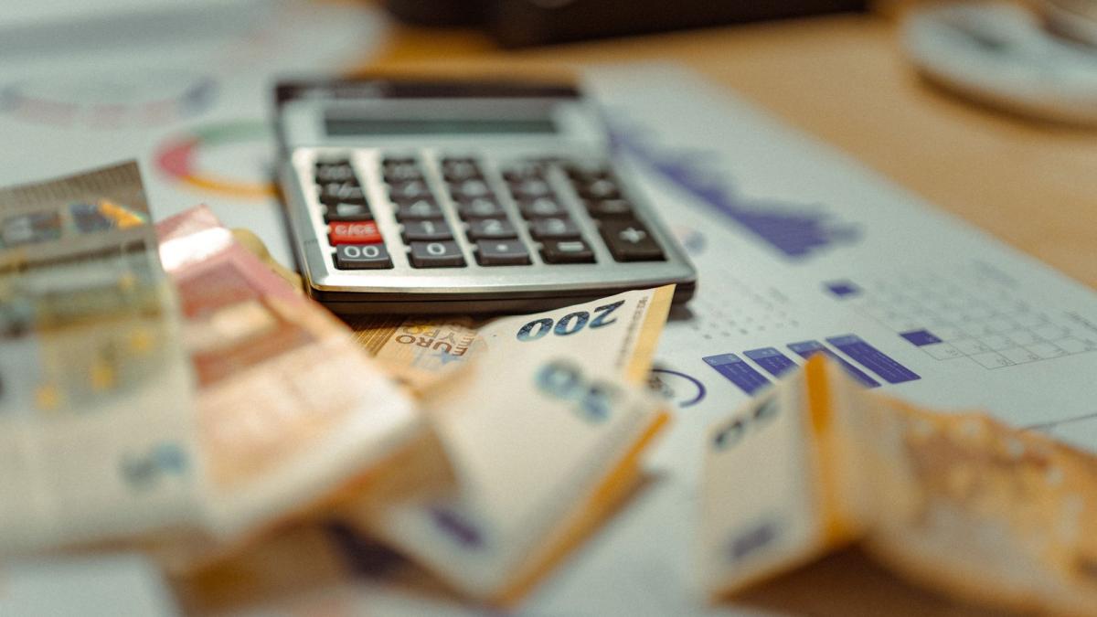 Tisch mit Geldscheinen und einem Taschenrechner zur Aktivrente für Gesellschafter Geschäftsführer.