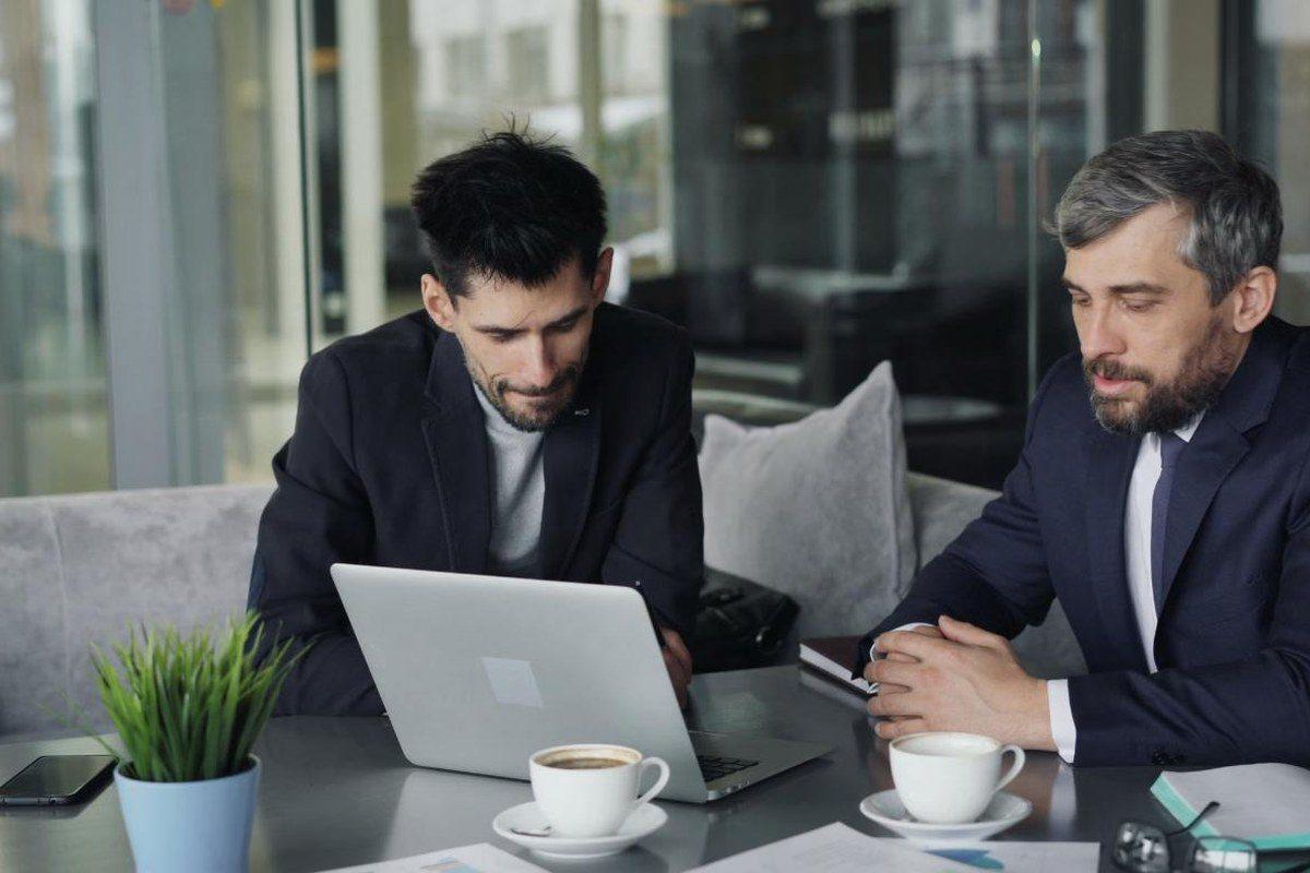 Zwei Personen besprechen Unterlagen an einem Laptop
