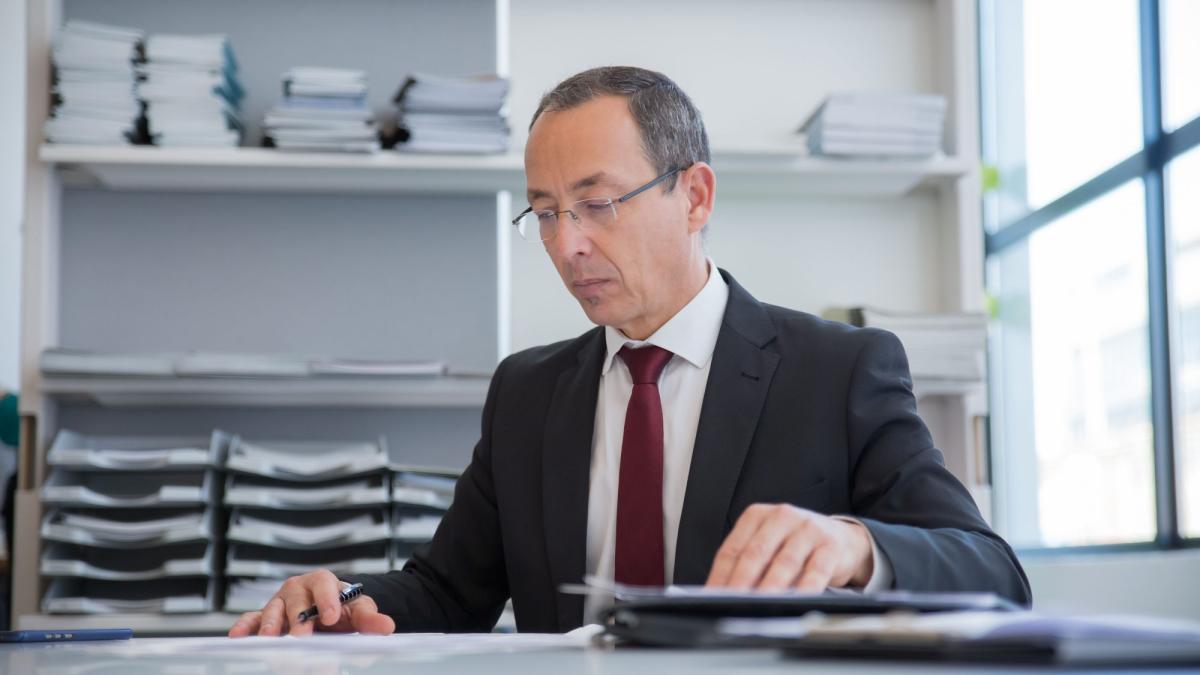 GmbH-Geschäftsführer arbeitet am Schreibtisch mit Unterlagen zum 676 €-Trick.