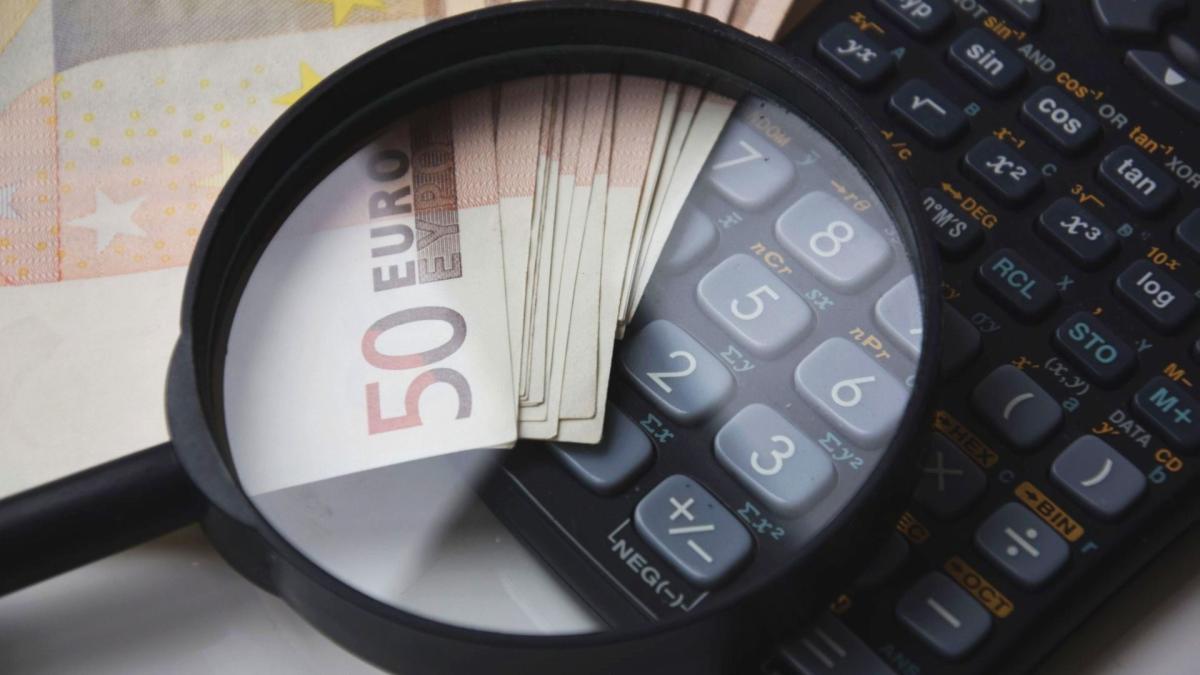 Mit Lupe auf 50-Euro-Scheine und Taschenrechner, passend zum angemessenen Geschäftsführergehalt.
