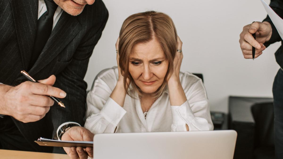 Gestresste Frau am Computer mit Diskussion über angemessenes Geschäftsführergehalt.