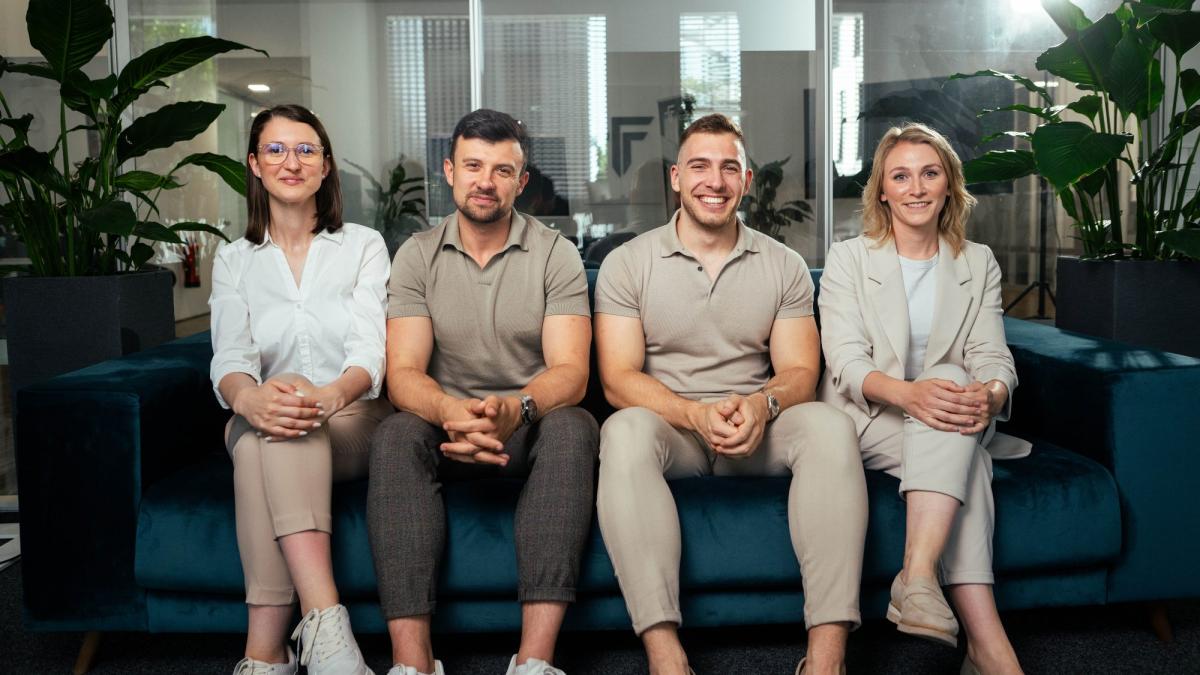 Teamfoto im Büro mit vier Personen auf einer Couch, passend zum Thema angemessenes Geschäftsführergehalt.
