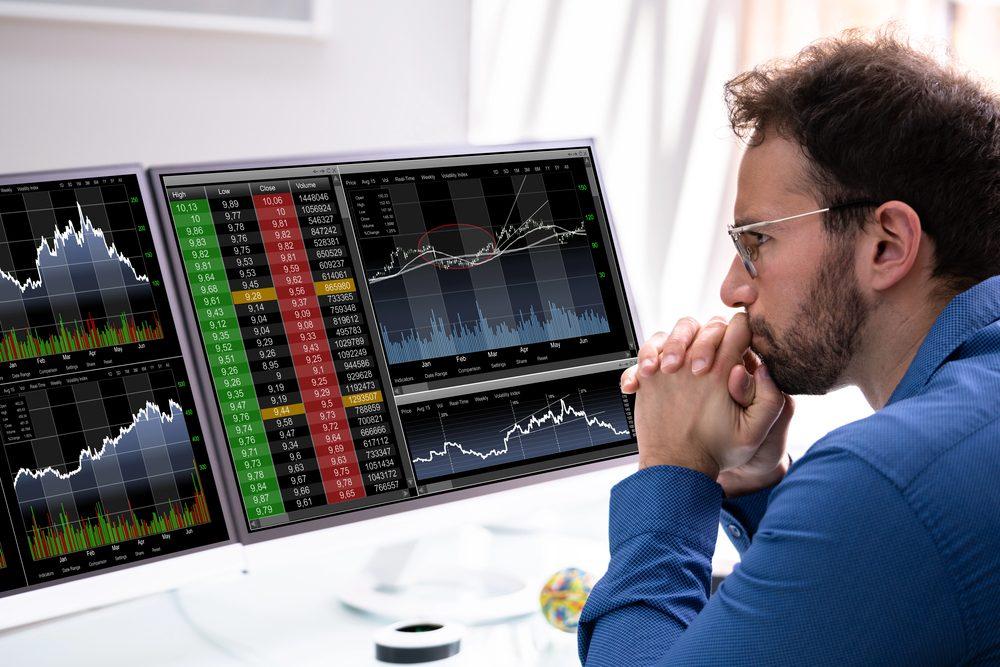 Trader beobachtet Charts auf Monitoren während des Aktien-Screenings.