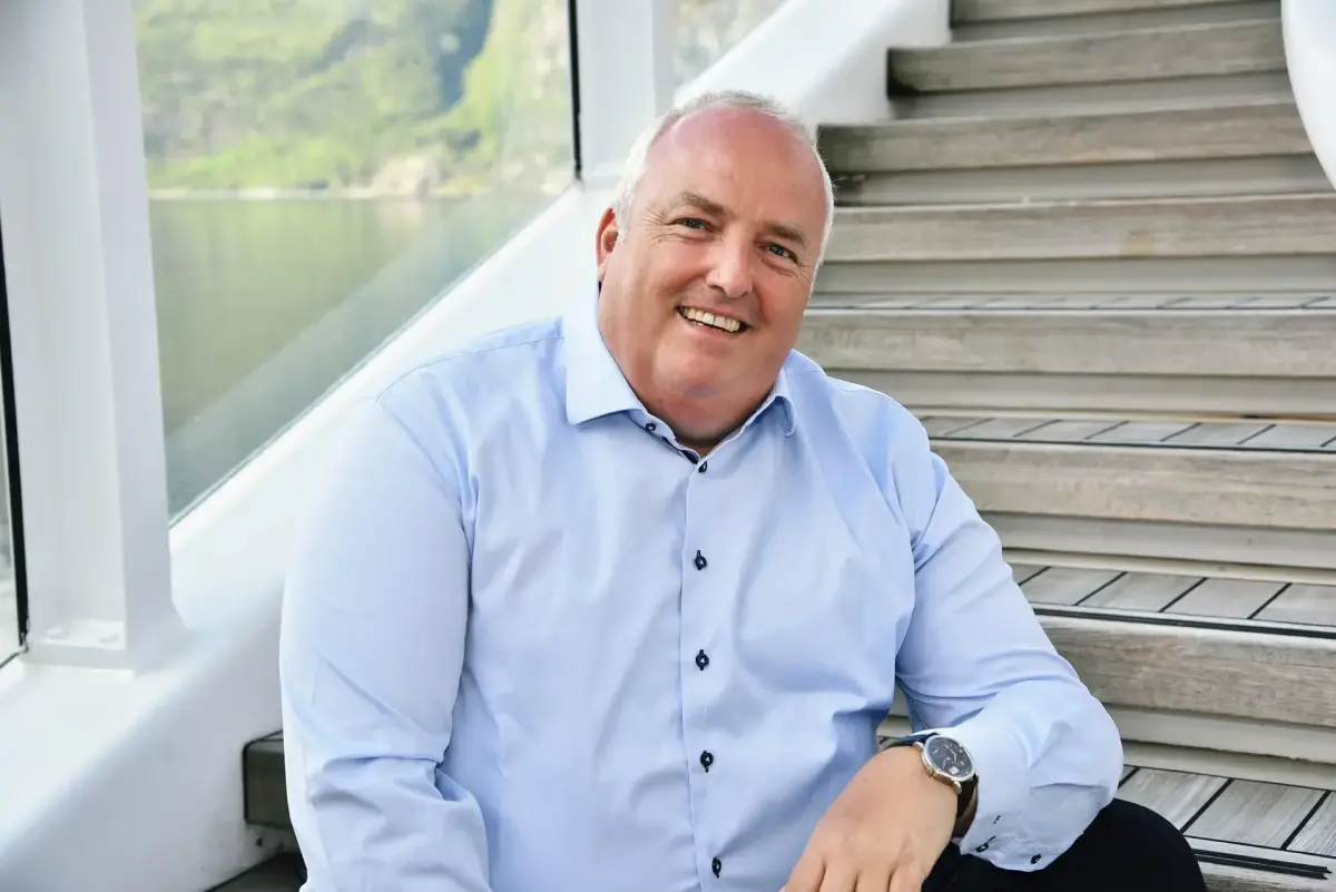 Mario Lüddemann sitzt lachend auf einer Treppe und vermittelt Seriosität.