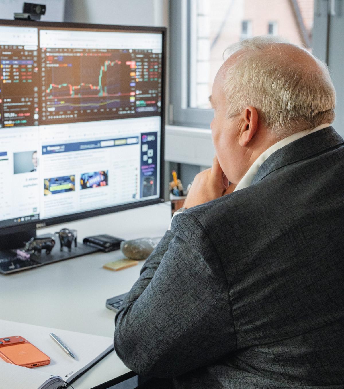 Mario Lüddemann schaut auf den Bildschirm mit Trading-Daten und Charts.