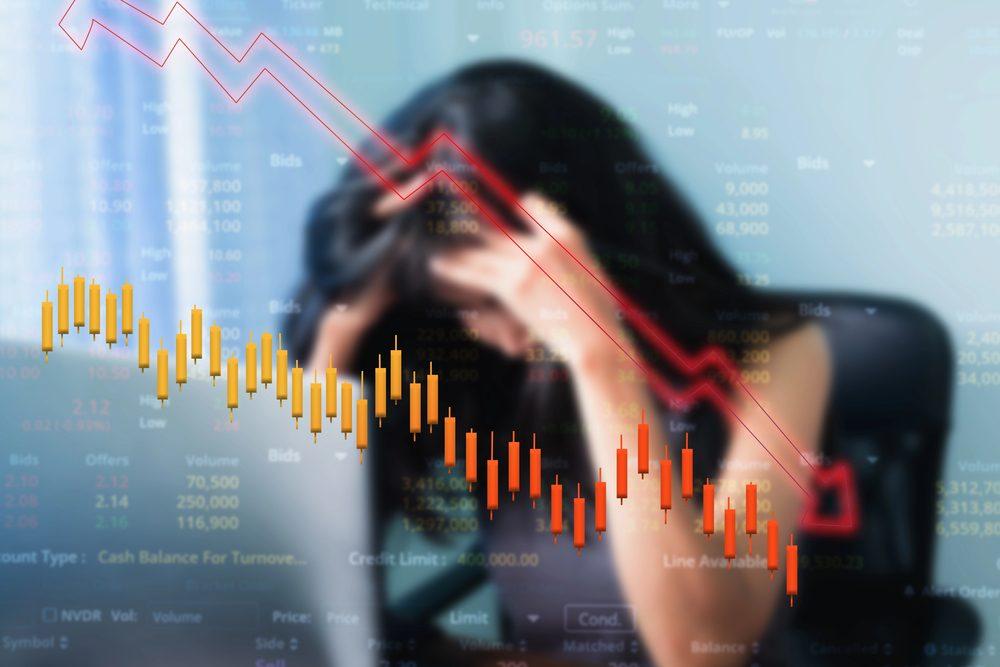 Eine gestresste Traderin mit gesenktem Kopf zeigt emotionale Hürden beim Trading.