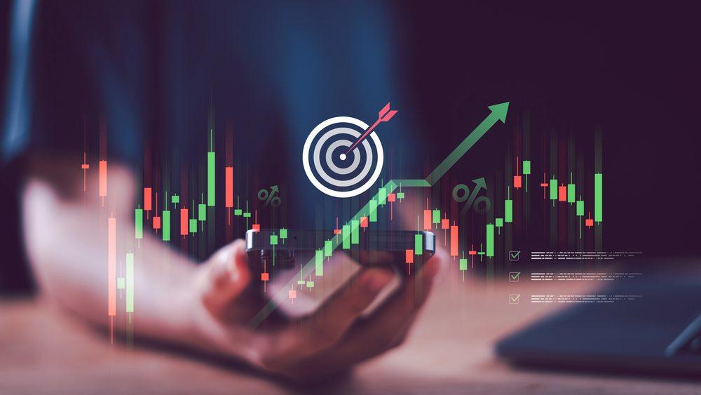 Ein Anleger zeigt auf eine Grafik, die mit Zeit im Markt und Wachstum symbolisiert.