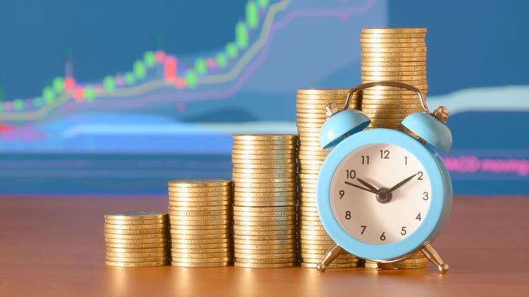 Uhr und Münzstapel symbolisieren die Bedeutung von Zeit im Markt beim Investieren.