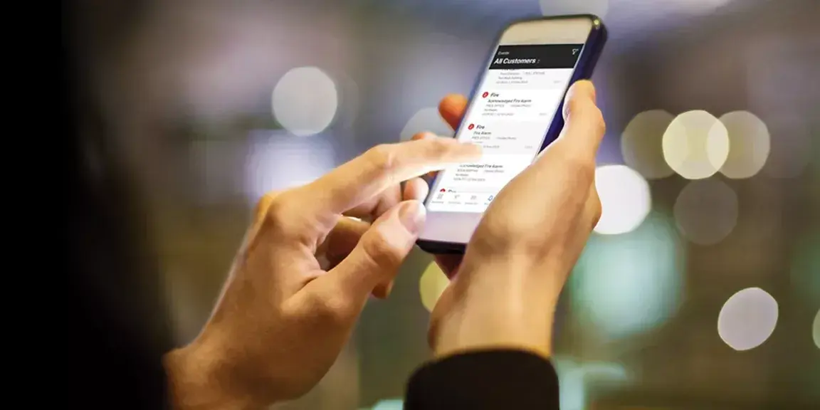 Eine Person prüft einen Selbsttestmelder über eine App auf dem Smartphone.