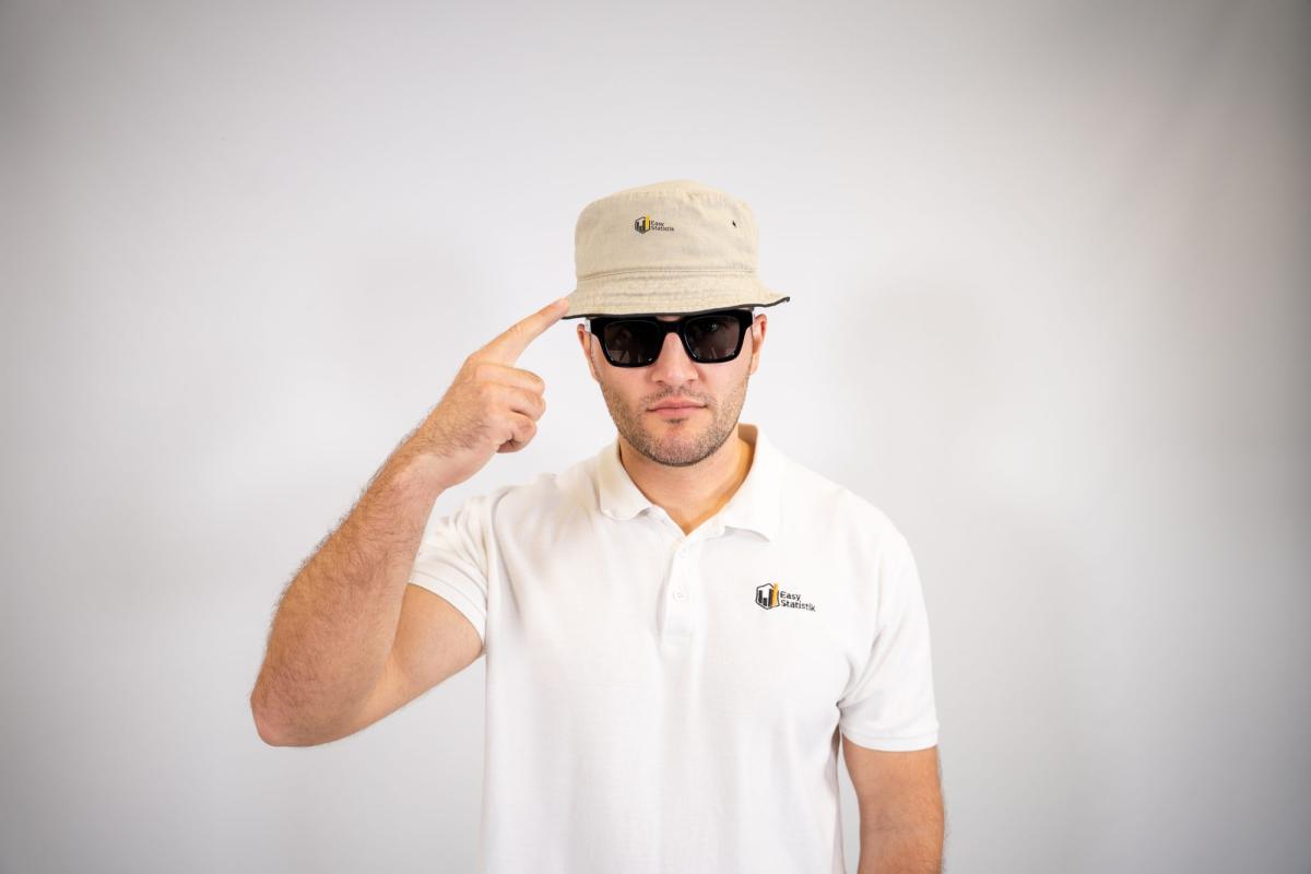 Mann mit Hut und Sonnenbrille zeigt auf seine Stirn, während er Likert Skalen auswertet.