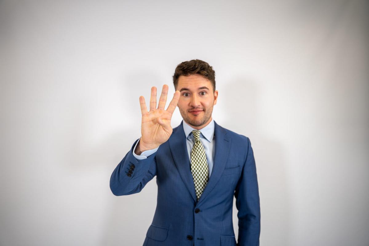 Mann im Anzug zeigt vier Finger, ein Symbol für die Wahl zwischen Stata oder SPSS.
