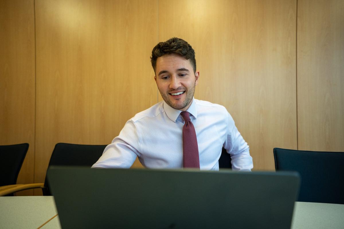 Mann am Computer lächelt während er Datenbereinigung in Studien durchführt.