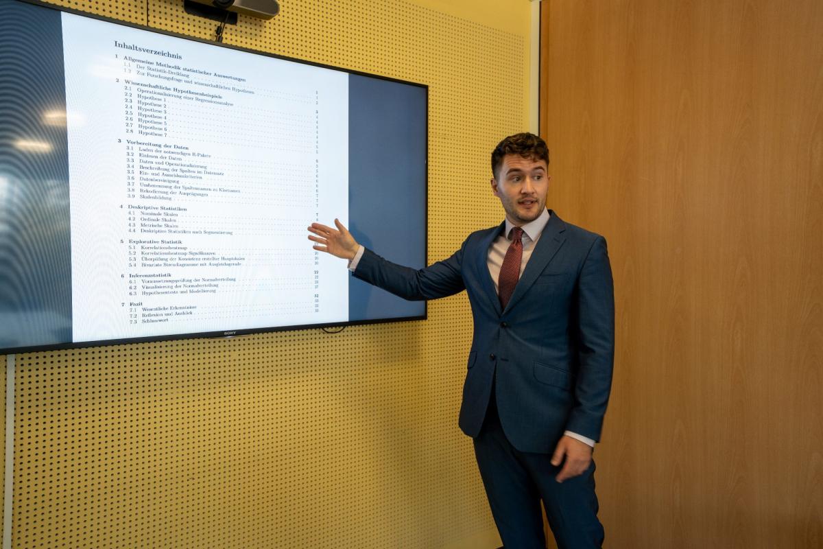 Ein Mann präsentiert auf einem Bildschirm Informationen zu Statistiksoftware für Projekte.