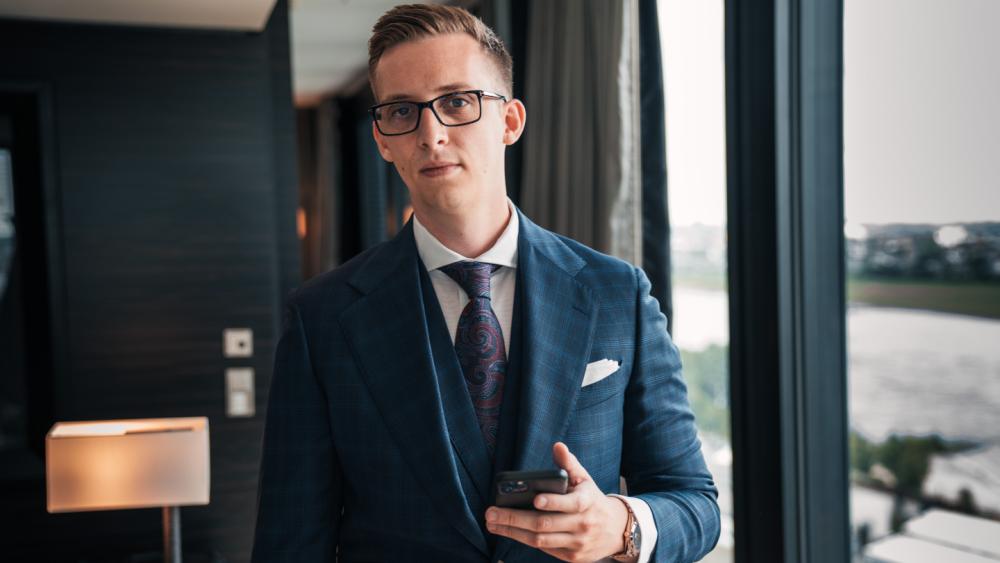 Mann im Anzug mit Telefon, der über B2B-Kunden über Social Media informiert.