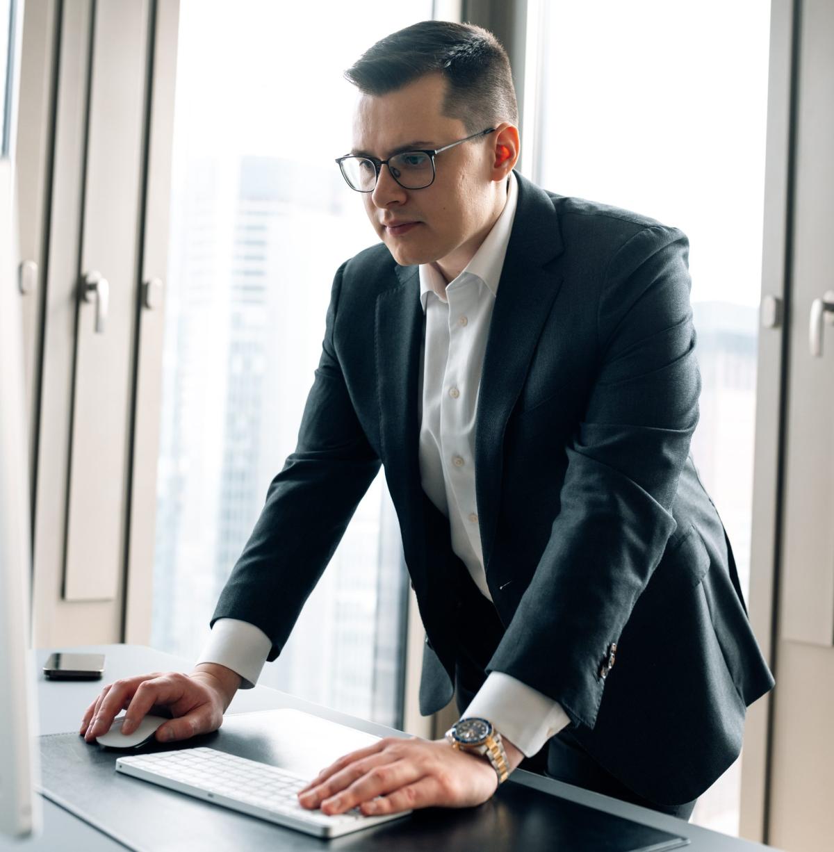 Mann in Anzug bei der Büroarbeit zu Aktien-Investments über eine Holding.