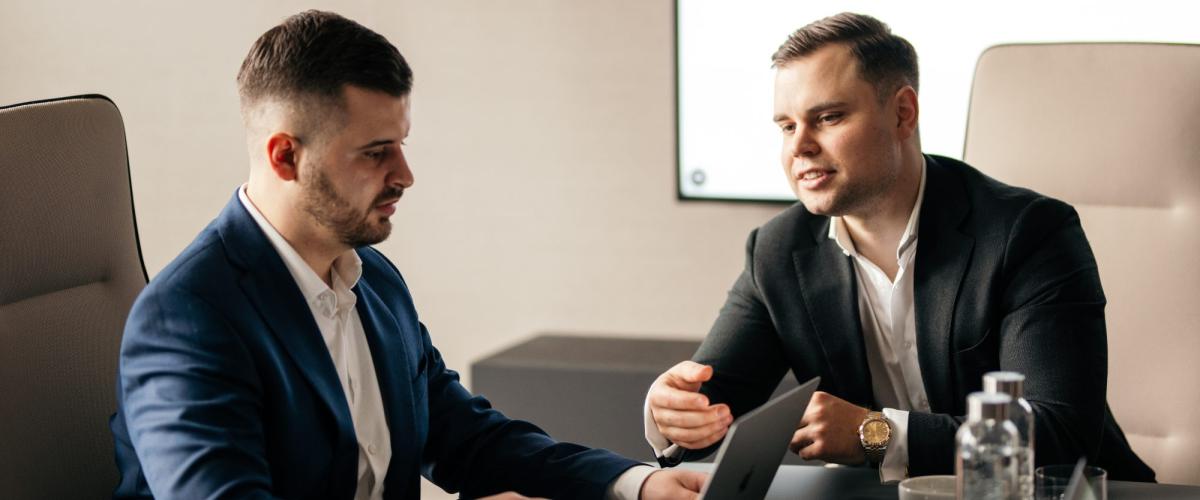 Zwei Männer im Anzug diskutieren die Rentenversicherungspflicht für Selbstständige.