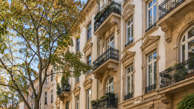 Schöne Altbau-Fassade in Mainz mit Balkonen und Bäumen, relevant für Wohngebäudeversicherung.