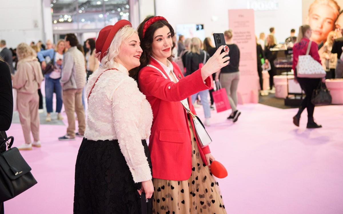 Zwei Frauen machen ein Selfie auf einer Beauty-Messe, ideal für Beauty Business Consulting.
