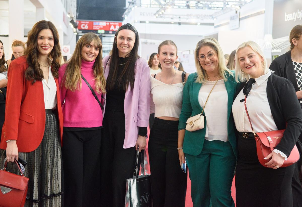 Gruppe von Frauen in eleganten Outfits bei einer Veranstaltung zur Unternehmensberatung für Kosmetikstudios.