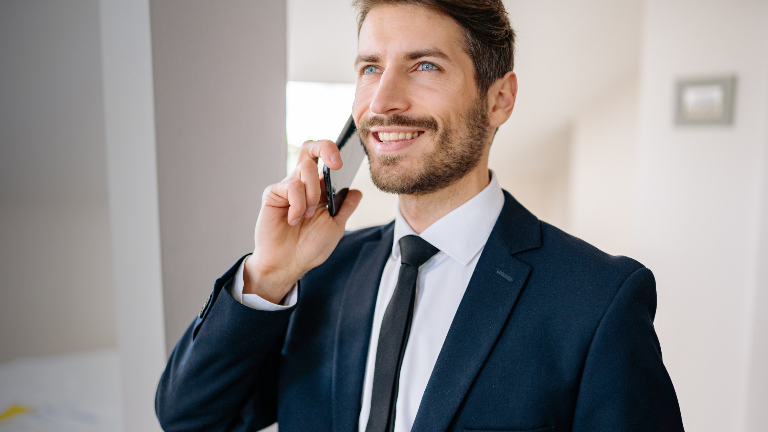 Mann im Anzug telefoniert, während er über Nachfassen im Vertrieb spricht.