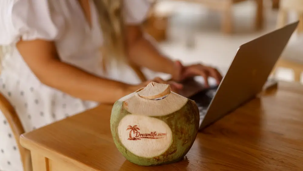 Eine Kokosnuss steht auf einem Tisch neben einem Laptop, ideal für Social Recruiting.