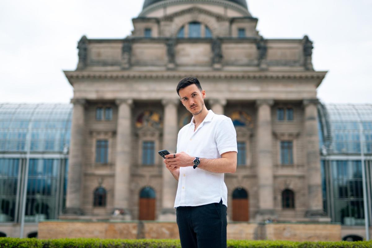 Ein Mann steht vor dem Reichstagsgebäude und blickt auf sein Smartphone – passend zum Thema LinkedIn Ads.