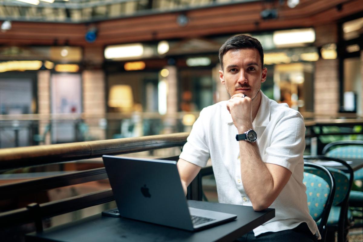 Ein nachdenklicher Mann mit Laptop reflektiert über Wachstum durch Mindset.