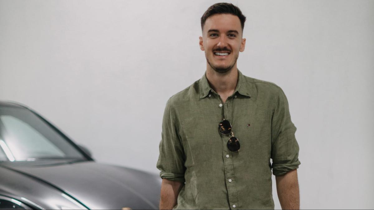 Ein Mann steht lächelnd neben einem Auto und spricht über Entscheidungen treffen.