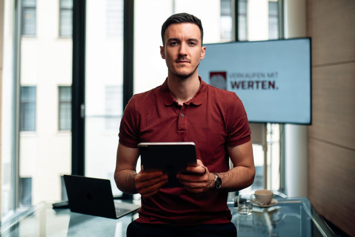 Mann hält Tablet und steht vor Bildschirm mit der Aufschrift Umsatz sofort verdoppeln.