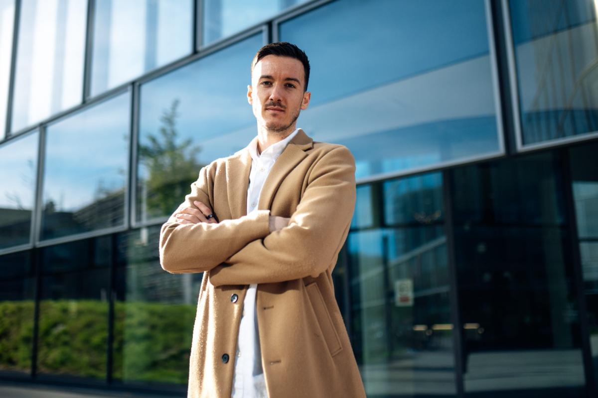 Ein Berater steht mit verschränkten Armen vor einem modernen Bürogebäude – passend zur LinkedIn Kundengewinnung.