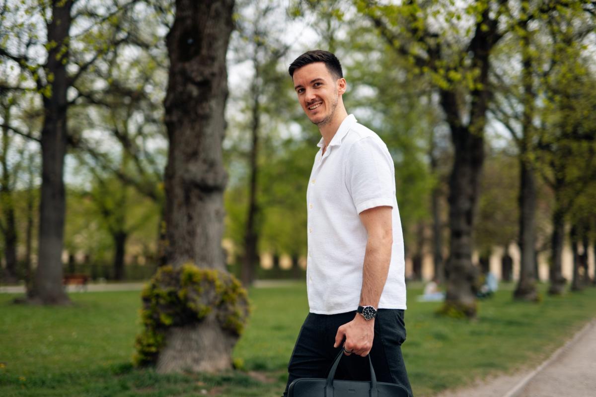 Ein Mann in weißem Poloshirt geht mit einer Tasche durch einen Park – passend zum Thema LinkedIn-Kunden gewinnen.