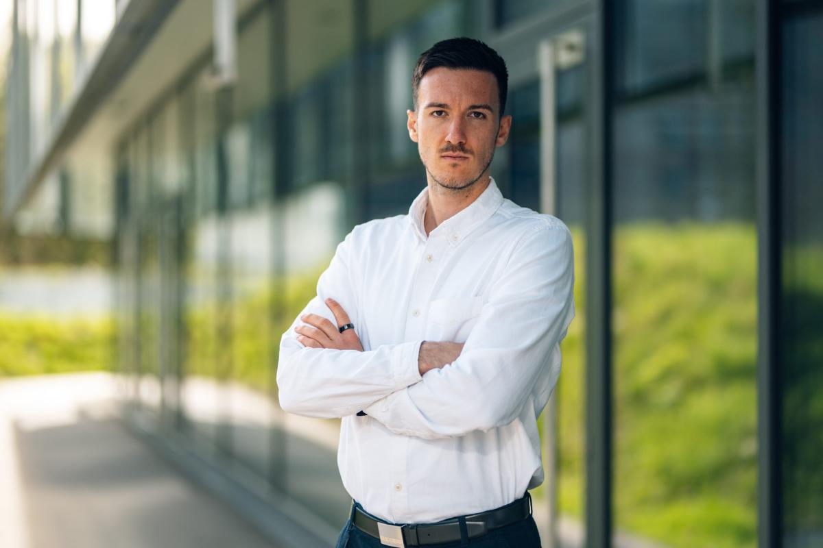 LinkedIn-Kunden gewinnen: Ein Mann im weißen Hemd steht mit verschränkten Armen vor einer Glasfassade.