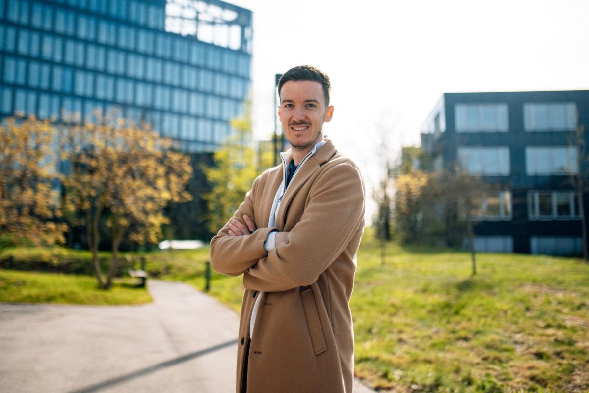 Ein lächelnder Mann steht mit verschränkten Armen vor Bürogebäuden; der LinkedIn Algorithmus erreicht neue Zielgruppen.