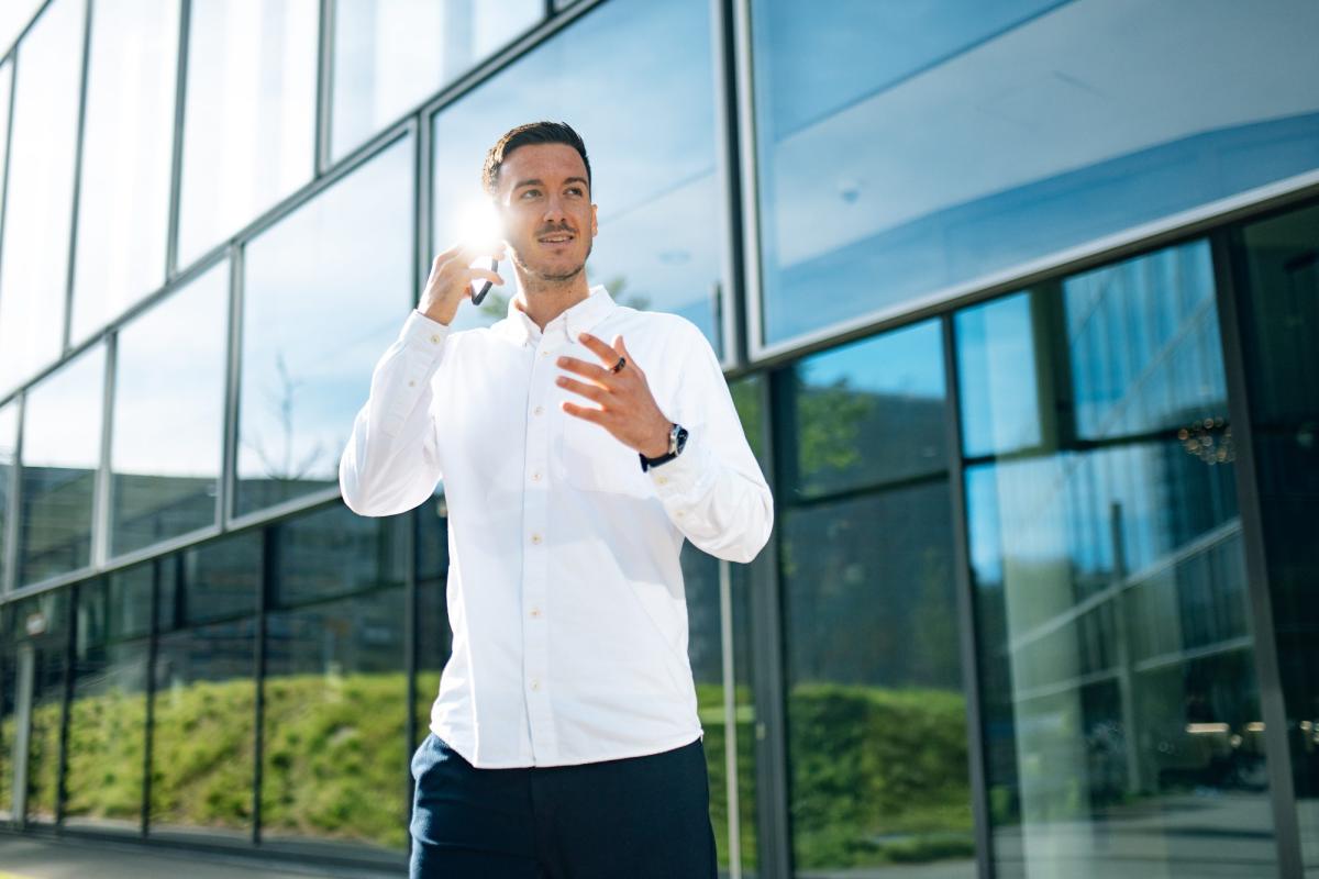 Ein Mann steht vor einem modernen Bürogebäude und gestikuliert zum LinkedIn Algorithmus.