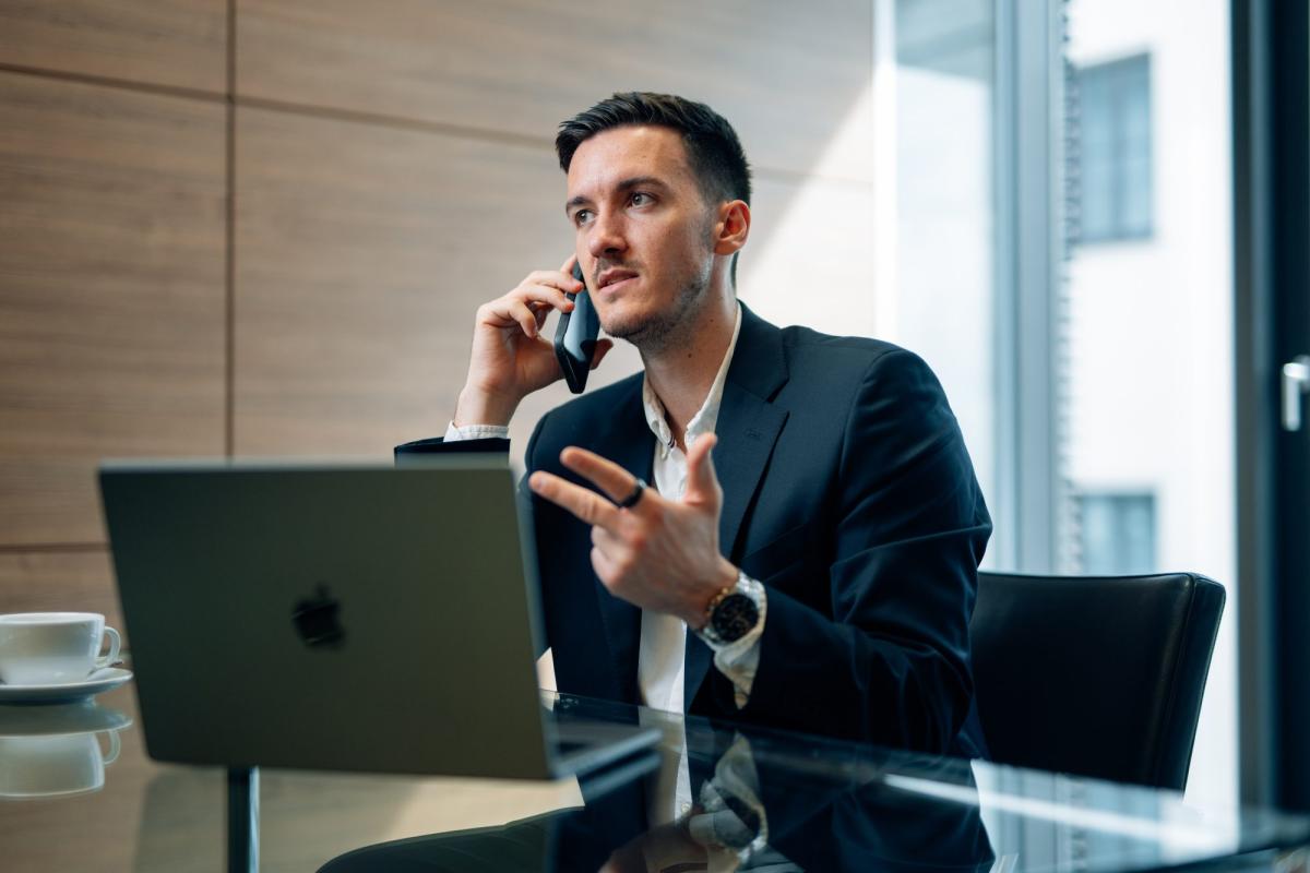 Mann im Anzug telefoniert und diskutiert über Scam Coaches.