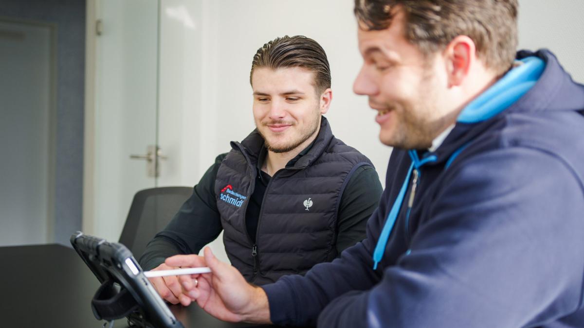 Zwei Fachleute besprechen die Photovoltaik Dachstatik am Tablet.