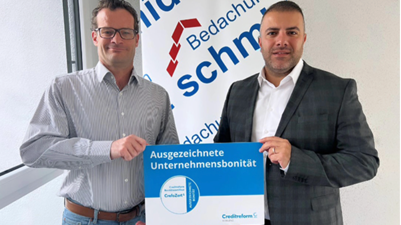 Zwei Männer halten das CrefoZert für ausgezeichnete Unternehmensbonität in der Hand.
