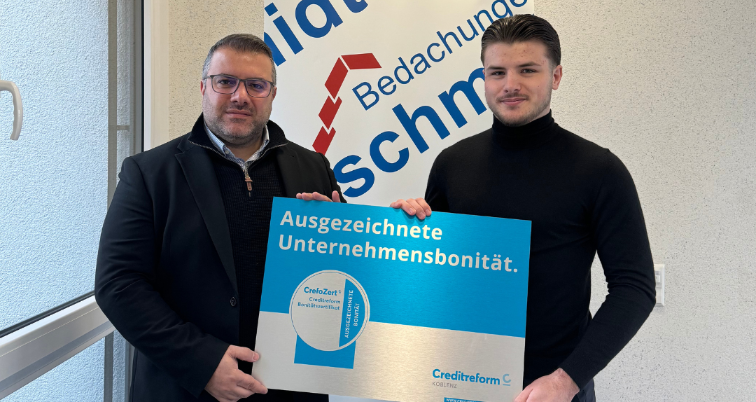 Zwei Männer halten das CrefoZert-Siegel für Unternehmensbonität von Bedachungen Schmidt.