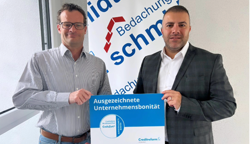 Zwei Männer halten das CrefoZert für ausgezeichnete Unternehmensbonität hoch.