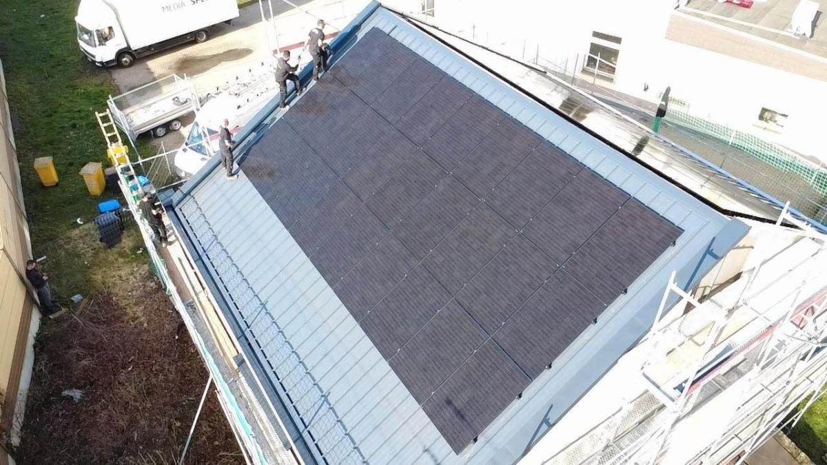 Handwerker installieren eine Photovoltaik-Anlage gemäß Solarpflicht 2027 auf einem Dach.