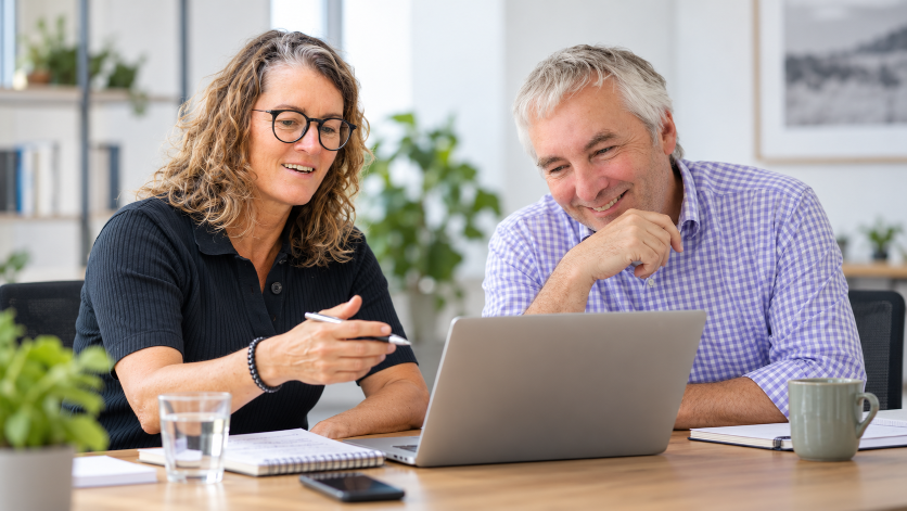 Zwei Personen arbeiten gemeinsam an einem Laptop und besprechen Online-Marketing für kleine Unternehmen.