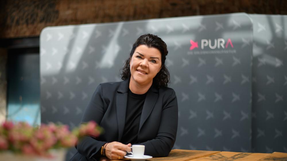 Frau in schwarzer Jacke sitzt am Tisch mit einem Kaffee für gelungene Events.
