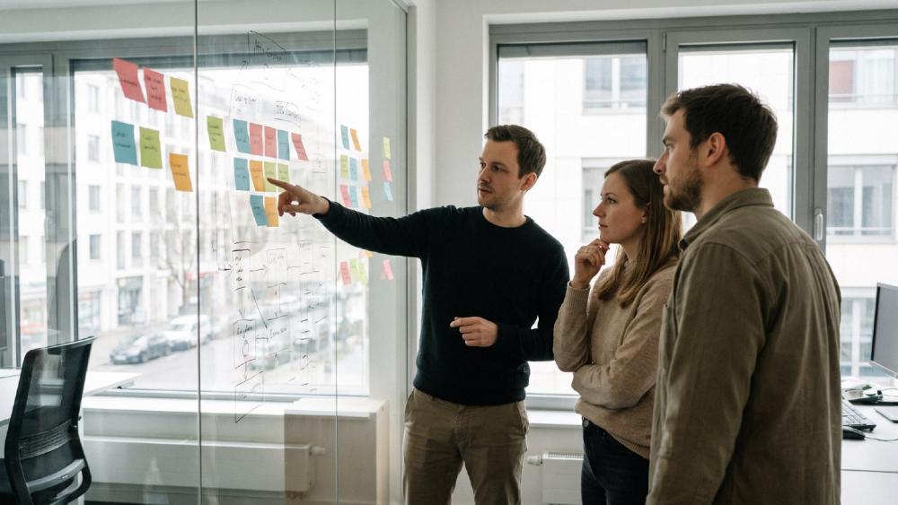 Team bespricht Forschungszulage für Softwareentwicklung an Pinnwand.